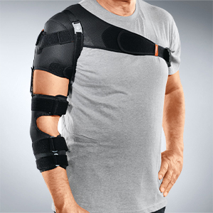 Mann in grauem Shirt, der eine schwarze Bandage am Oberarm trägt.